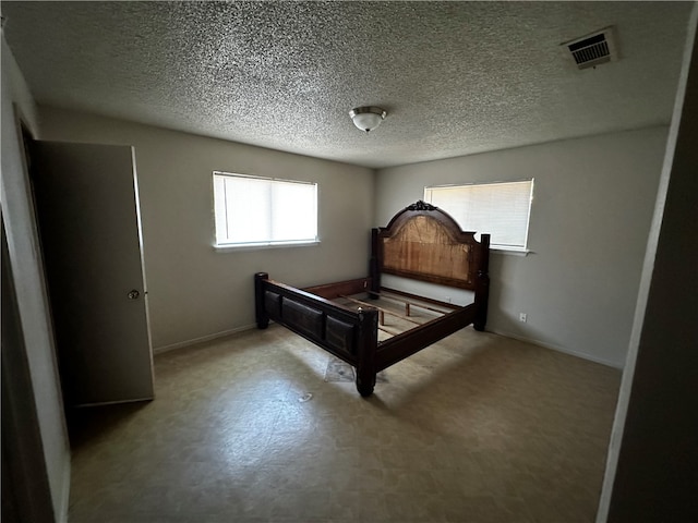 bedroom with a textured ceiling and multiple windows