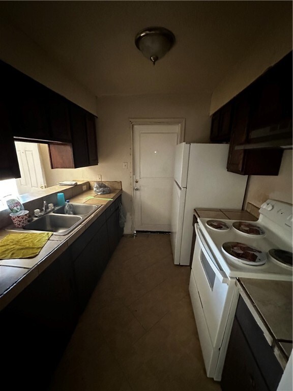 kitchen featuring dark brown cabinets, light tile patterned flooring, sink, and electric stove