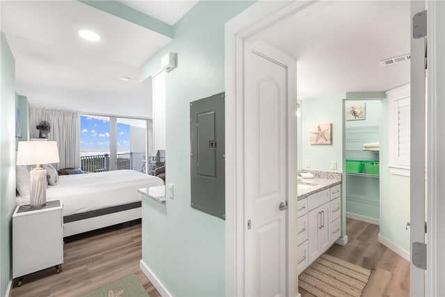 bedroom featuring light hardwood / wood-style floors, a wall of windows, and electric panel