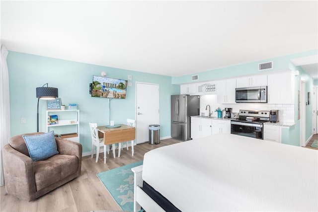 bedroom featuring light hardwood / wood-style floors, sink, and stainless steel refrigerator