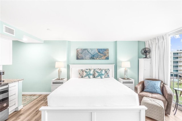 bedroom with floor to ceiling windows and light wood-type flooring