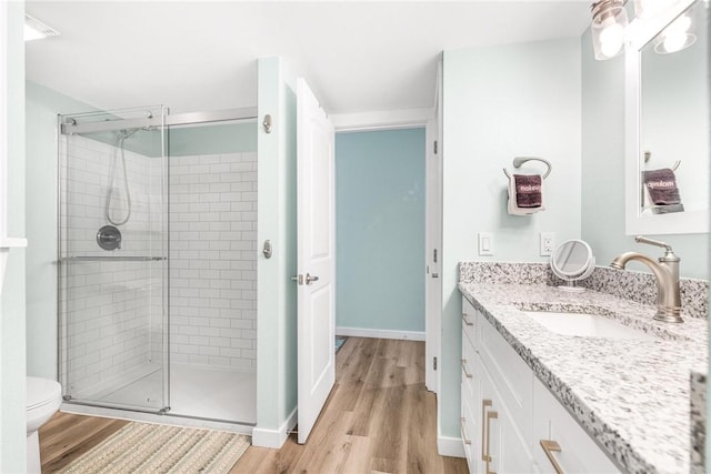 bathroom featuring wood-type flooring, vanity, toilet, and walk in shower