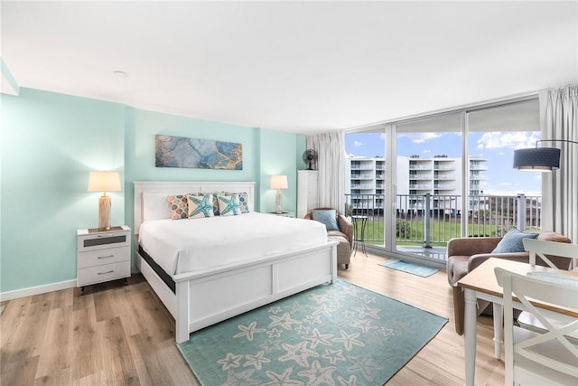 bedroom featuring access to exterior, expansive windows, and light hardwood / wood-style floors