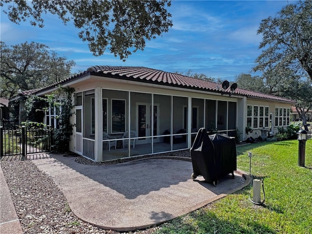 rear view of house featuring a yard, a sunroom, fence, and a tile roof