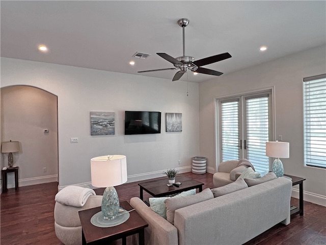 living area with dark wood-style floors, visible vents, baseboards, recessed lighting, and arched walkways