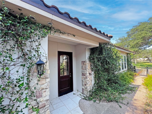 view of exterior entry with a tiled roof and stucco siding