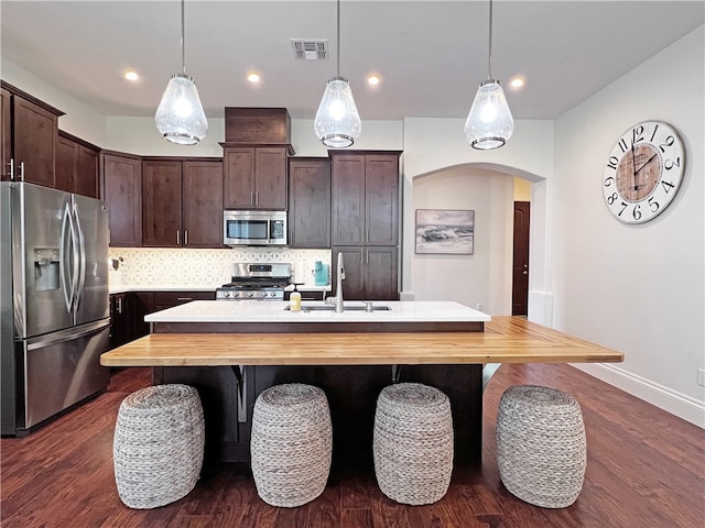 kitchen with visible vents, tasteful backsplash, arched walkways, appliances with stainless steel finishes, and dark brown cabinets