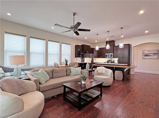 living room with dark wood-style floors, baseboards, recessed lighting, arched walkways, and ceiling fan