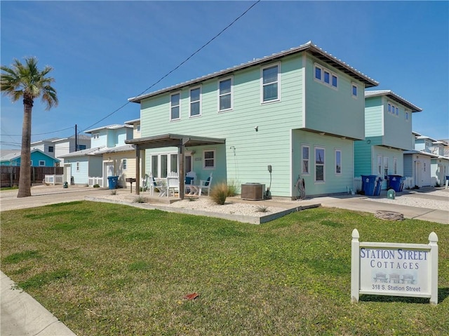 rear view of property featuring central AC unit, a patio area, and a lawn