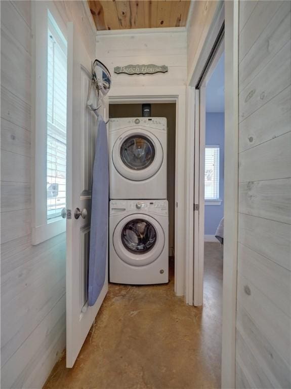 laundry room featuring stacked washer / drying machine and wood walls