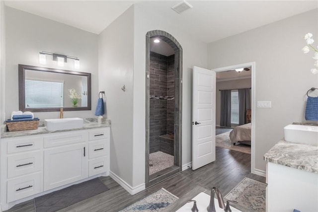 bathroom featuring vanity, a tile shower, wood finished floors, and ensuite bathroom