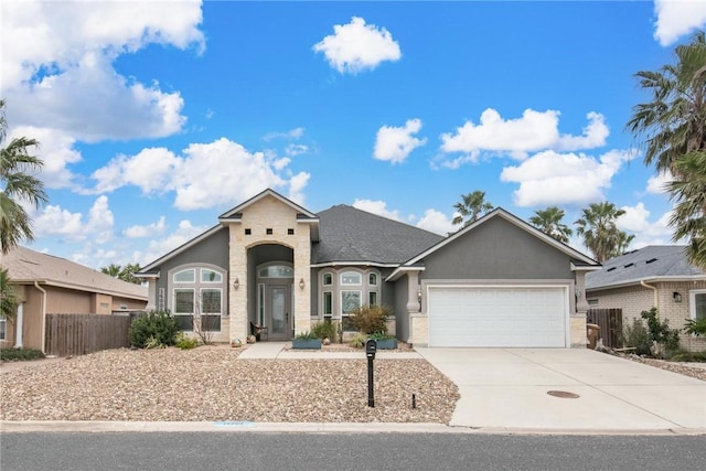 view of front of house with driveway, an attached garage, fence, and stucco siding