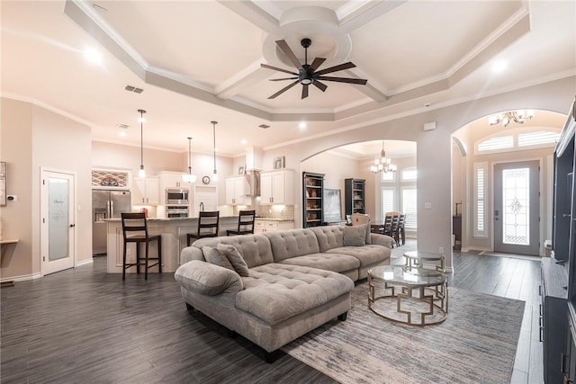 living room with dark wood-style floors, arched walkways, visible vents, and ceiling fan with notable chandelier