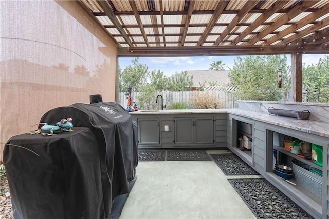 view of patio featuring area for grilling, fence, and an outdoor kitchen