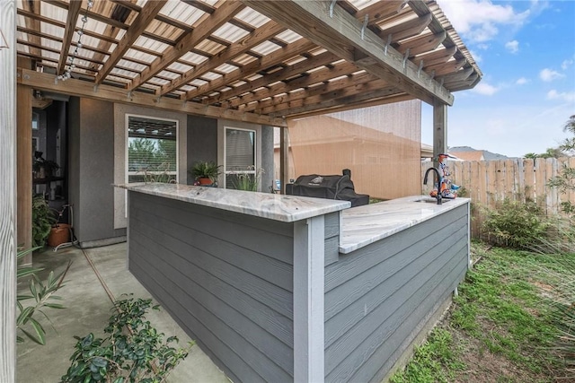 view of patio featuring outdoor dry bar and fence