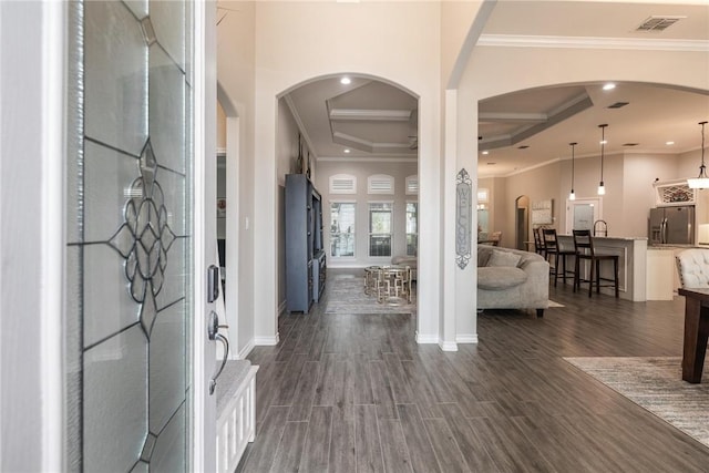 entryway with dark wood-style floors, ornamental molding, visible vents, and baseboards