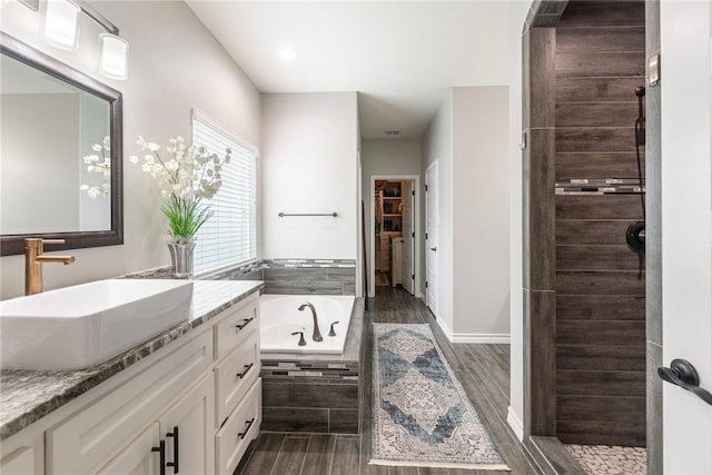 bathroom with tiled shower, a spacious closet, vanity, wood finish floors, and a bath