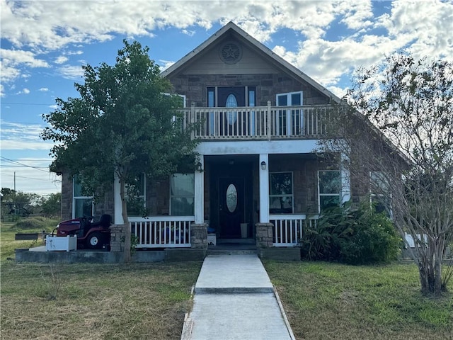 view of front of property featuring a balcony, a front lawn, and covered porch