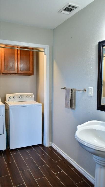 washroom featuring washing machine and dryer, cabinets, and dark wood-type flooring