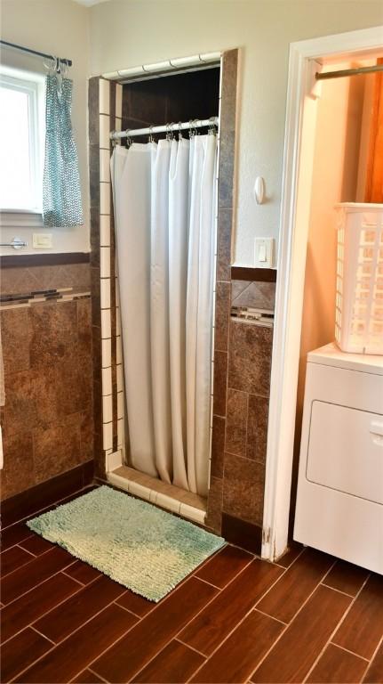 bathroom featuring washer / clothes dryer, walk in shower, and tile walls