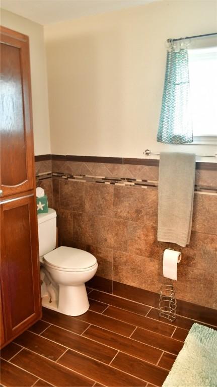 bathroom with toilet and tile walls