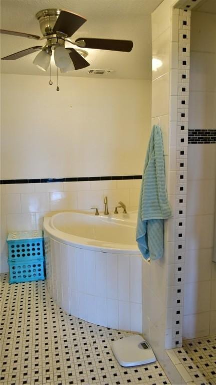 bathroom with ceiling fan, tile patterned flooring, and tile walls