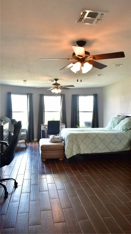 bedroom with ceiling fan, dark wood-type flooring, and multiple windows