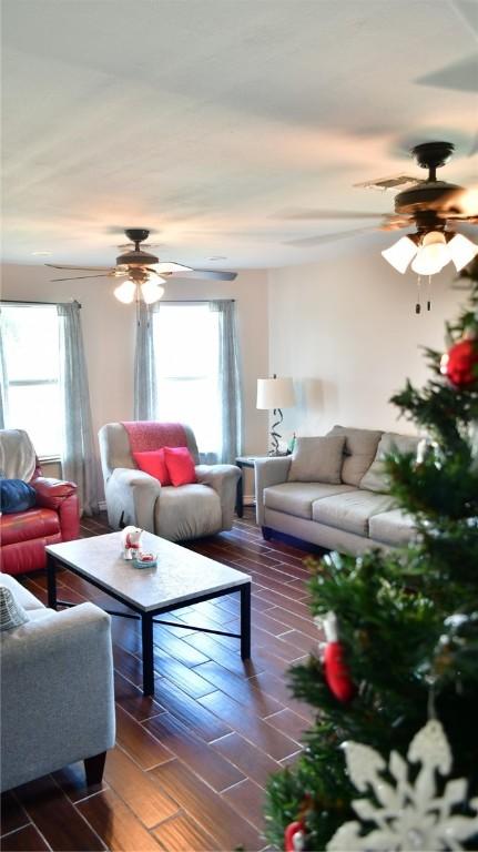 living room featuring dark hardwood / wood-style flooring, ceiling fan, and a healthy amount of sunlight