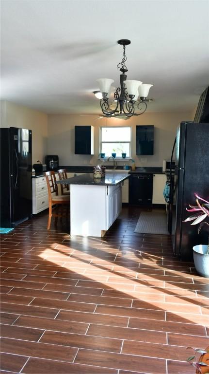 kitchen with white cabinets, sink, black appliances, decorative light fixtures, and a chandelier