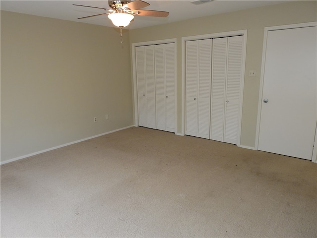 unfurnished bedroom with multiple closets, carpet, and ceiling fan