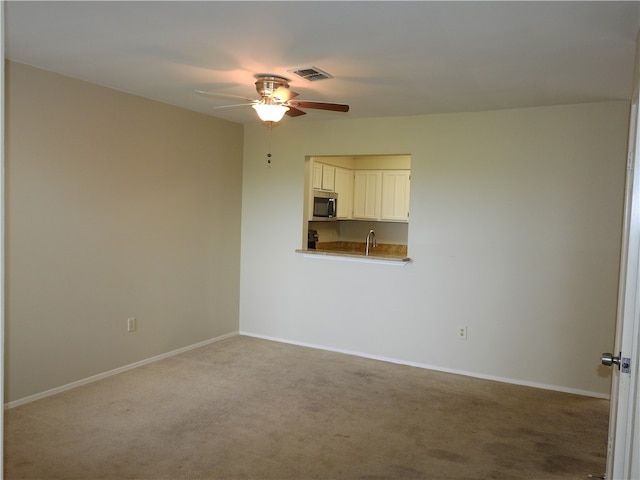 carpeted empty room featuring ceiling fan