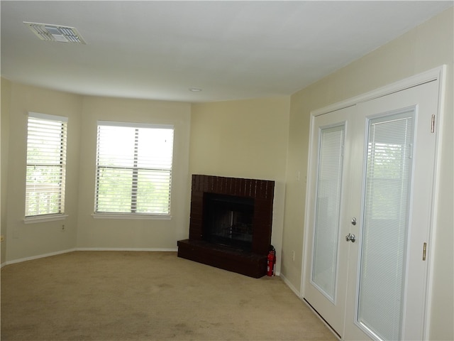 unfurnished living room with a brick fireplace and light carpet