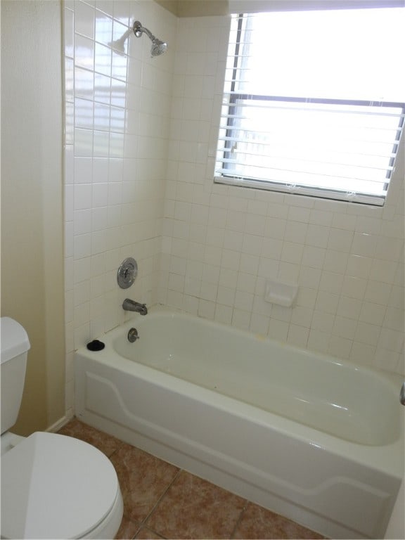 bathroom featuring toilet, tiled shower / bath, tile patterned flooring, and a healthy amount of sunlight