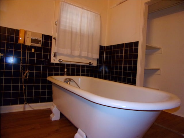 bathroom featuring hardwood / wood-style floors, a bathtub, and tile walls