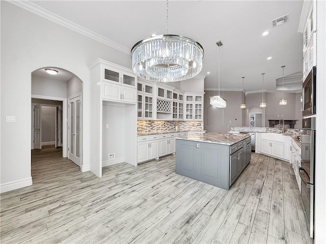 kitchen with white cabinets, a notable chandelier, arched walkways, and visible vents