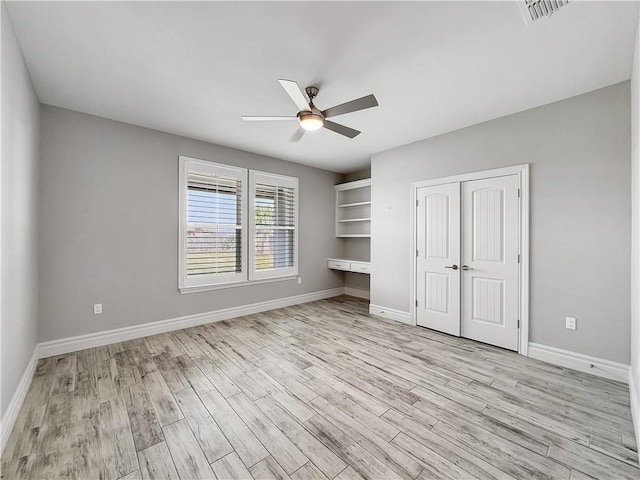 unfurnished bedroom featuring baseboards, visible vents, light wood-style flooring, ceiling fan, and a closet