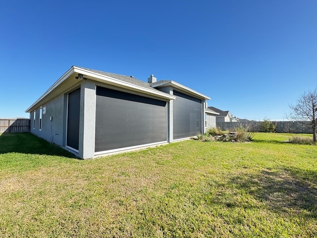 view of side of home featuring a lawn, fence, and stucco siding