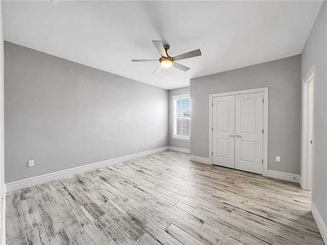 unfurnished bedroom featuring light wood finished floors, ceiling fan, a closet, and baseboards