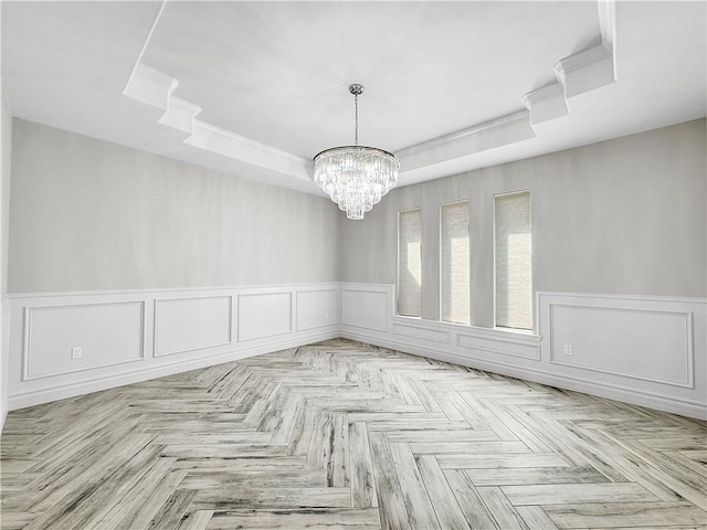 unfurnished room featuring a tray ceiling, a wainscoted wall, and a chandelier