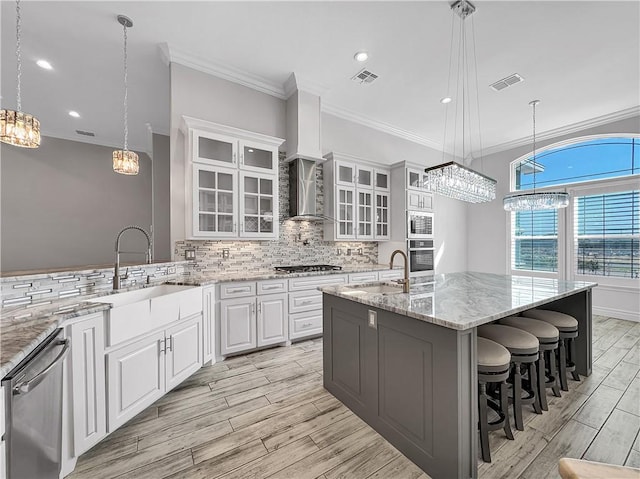 kitchen featuring visible vents, a sink, tasteful backsplash, stainless steel appliances, and wall chimney range hood