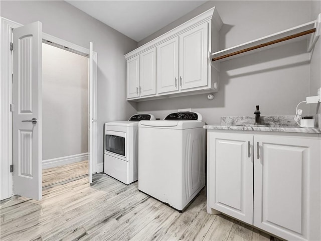 clothes washing area featuring light wood finished floors, cabinet space, baseboards, and separate washer and dryer