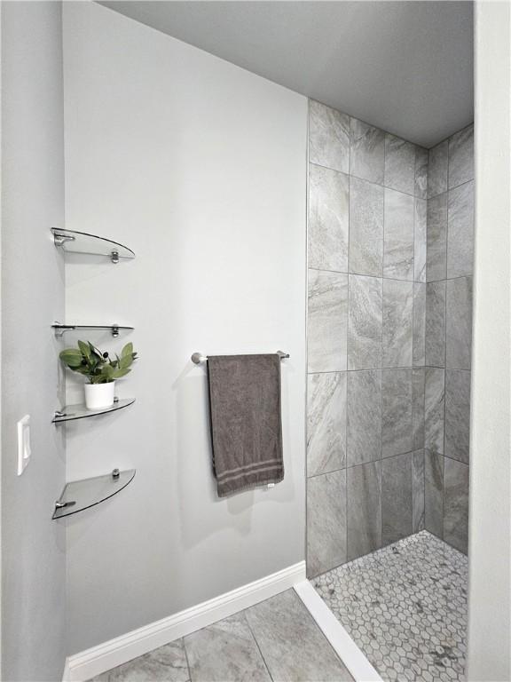 bathroom featuring baseboards and tiled shower