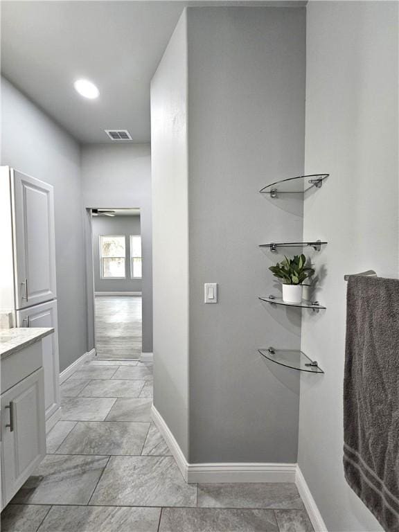 hall featuring baseboards and visible vents