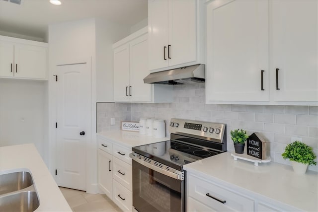 kitchen with decorative backsplash, stainless steel range with electric stovetop, light tile patterned floors, white cabinetry, and range hood