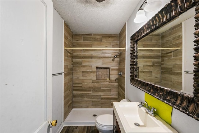 bathroom with a tile shower, sink, a textured ceiling, and toilet