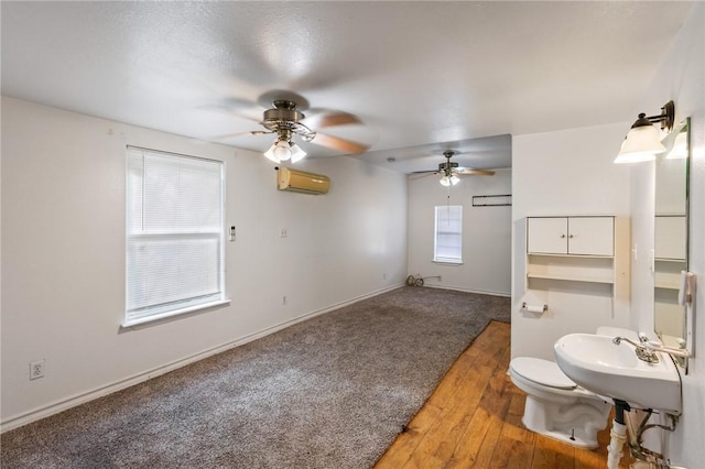 bathroom featuring a wall unit AC, a wealth of natural light, hardwood / wood-style floors, and ceiling fan