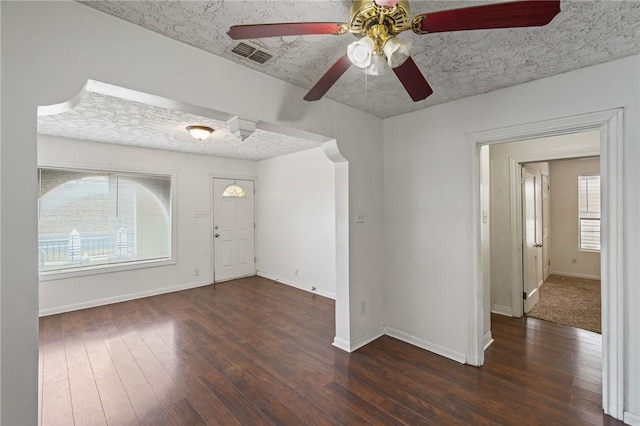 unfurnished room featuring dark hardwood / wood-style flooring, a textured ceiling, ceiling fan, and a healthy amount of sunlight