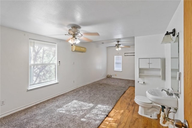 bathroom featuring sink, hardwood / wood-style flooring, ceiling fan, toilet, and a wall mounted AC