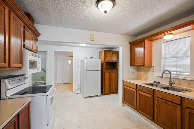 kitchen with a textured ceiling, decorative backsplash, white appliances, and sink