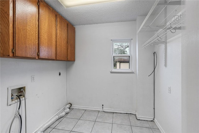 laundry area featuring light tile patterned floors, hookup for a washing machine, cabinet space, hookup for an electric dryer, and a textured ceiling